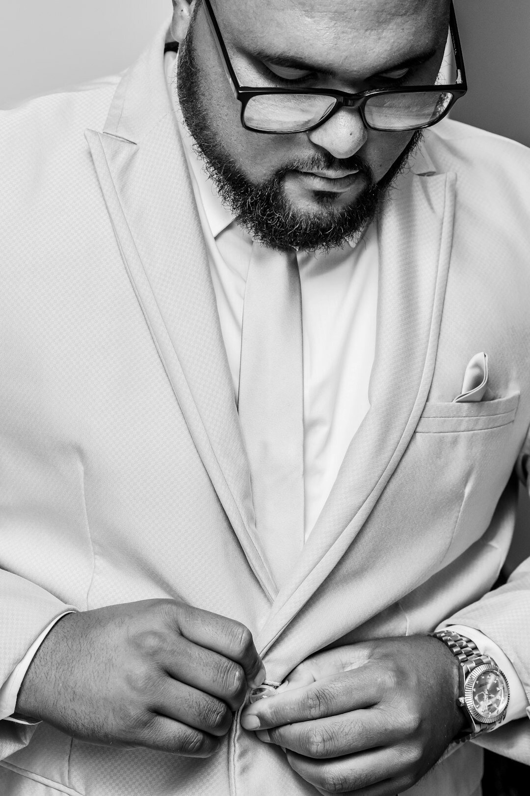 Studio portrait of a bearded man wearing glasses and a blazer
